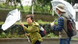 A woman have an umbrella turned inside out with strong wind in Tokyo on October 22, 2017. 
A powerful typhoon barrelled toward Japan on October 22, with heavy rain triggering landslides and delaying voting at one ballot station as millions struggled to the polls for a national election. 