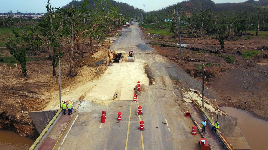 Workers repair a damaged road in Toa Alta, Puerto Rico, a month after Hurricane Maria ravaged the island.