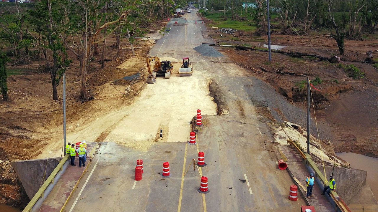 Workers repair a damaged road in Toa Alta, Puerto Rico, a month after Hurricane Maria ravaged the island.