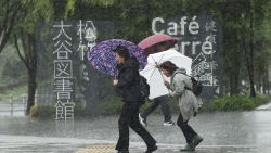 Pedestrians walk along a street under the rain in Tokyo on October 22, 2017.  
A powerful typhoon barrelled toward Japan on October 22, with heavy rain triggering landslides and delaying voting at one ballot station as millions struggled to the polls for a national election.  / AFP PHOTO / Kazuhiro NOGI        (Photo credit should read KAZUHIRO NOGI/AFP/Getty Images)