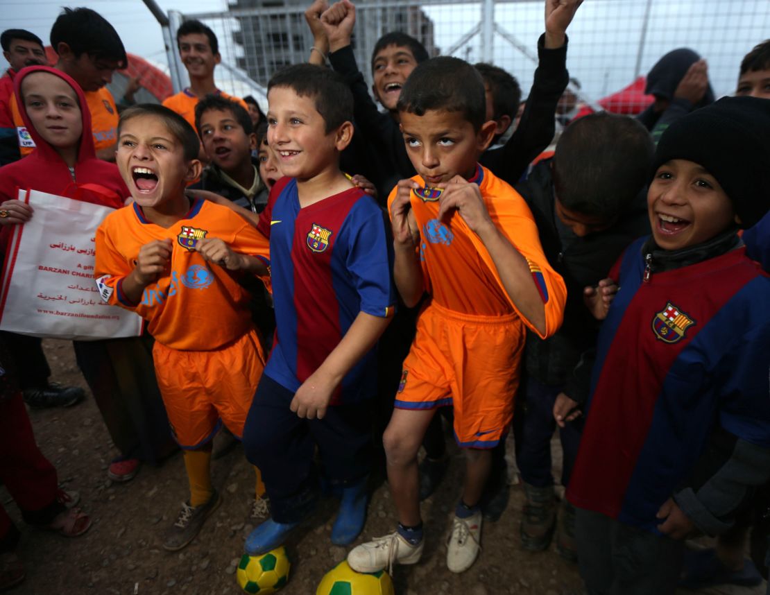 Displaced Iraqi children pose for a picture with FC Barcelona shirts  at the Harsham refugee camp, near Arbil.