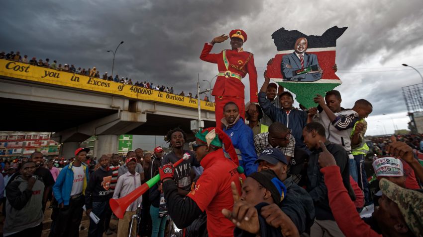 Supporters of Kenya's President Uhuru Kenyatta ride around and cheer, some holding a placard of Kenyatta, as they await his arrival as part of a campaign tour, in Githurai on the outskirts of Nairobi, Kenya Monday, Oct. 23, 2017. Kenyatta said Monday the presidential election must go ahead as planned on Thursday, despite a boycott by the main opposition candidate and the chief electoral officer's recent statement that he cannot guarantee that the polls would be credible. 
