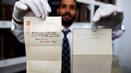 A picture taken on October 19, 2017, shows Gal Wiener, owner and manager of the Winner's auction house in Jerusalem, displays two notes written by Albert Einstein, in 1922, on hotel stationary from the Imperial Hotel in Tokyo Japan. 
A note that Albert Einstein gave to a courier in Tokyo, briefly describing his theory on happy living, has surfaced after 95 years and is up for auction in Jerusalem. / AFP PHOTO / MENAHEM KAHANA        (Photo credit should read MENAHEM KAHANA/AFP/Getty Images)