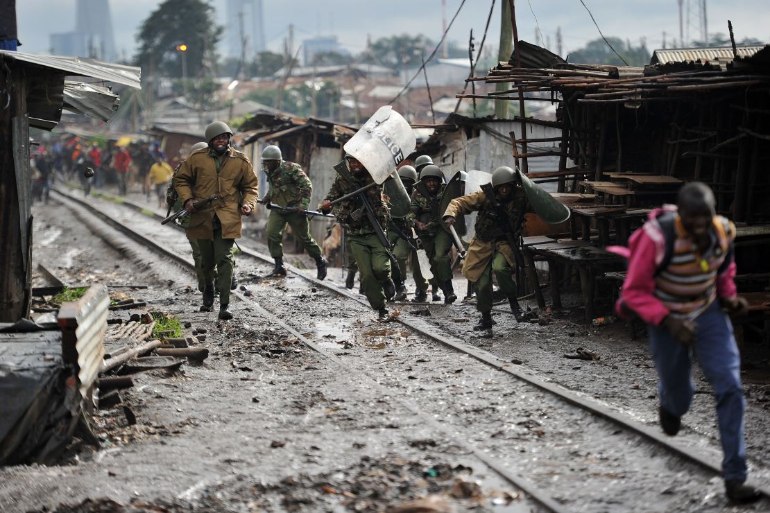Kenyan officers charge at stone-throwing residents during clashes in Kibera on Thursday