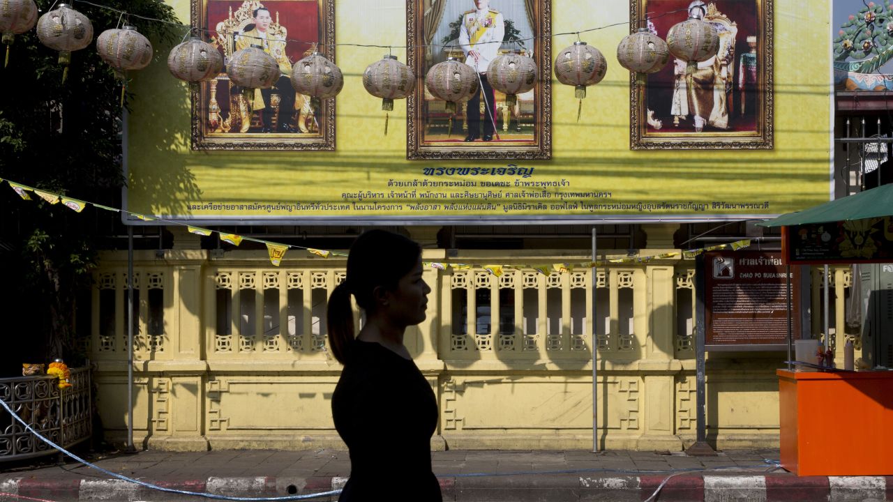 A woman walks past portraits of the late Thai King Bhumibol Adulyadej, left, and King Maha Vajiralongkorn, on Thursday in Bangkok. 