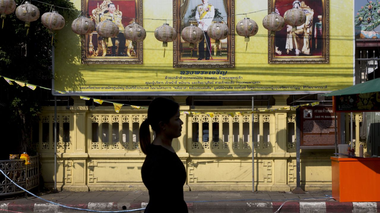 A woman walks past portraits of the late Thai King Bhumibol Adulyadej, left, and King Maha Vajiralongkorn, on Thursday in Bangkok.