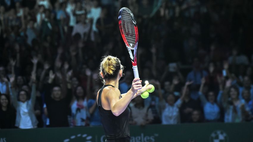 Simona Halep of Romania hits a ball for supporters after defeating Agnieszka Radwanska of Poland during the semi finals of the Women's Tennis Association (WTA) finals in Singapore on October 25, 2014. AFP PHOTO / ROSLAN RAHMAN        (Photo credit should read ROSLAN RAHMAN/AFP/Getty Images)
