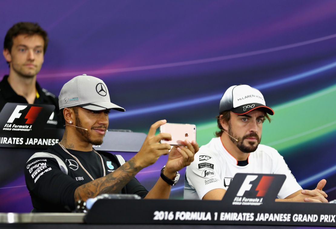 Hamilton (left) plays with his phone during a pre-race press conference at the 2016 Japanese GP 