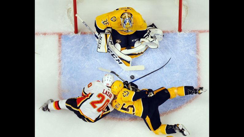 Nashville goalie Pekka Rinne makes a save as Calgary's Curtis Lazar and Nashville's Alexei Emelin collide in his crease on Tuesday, October 24.