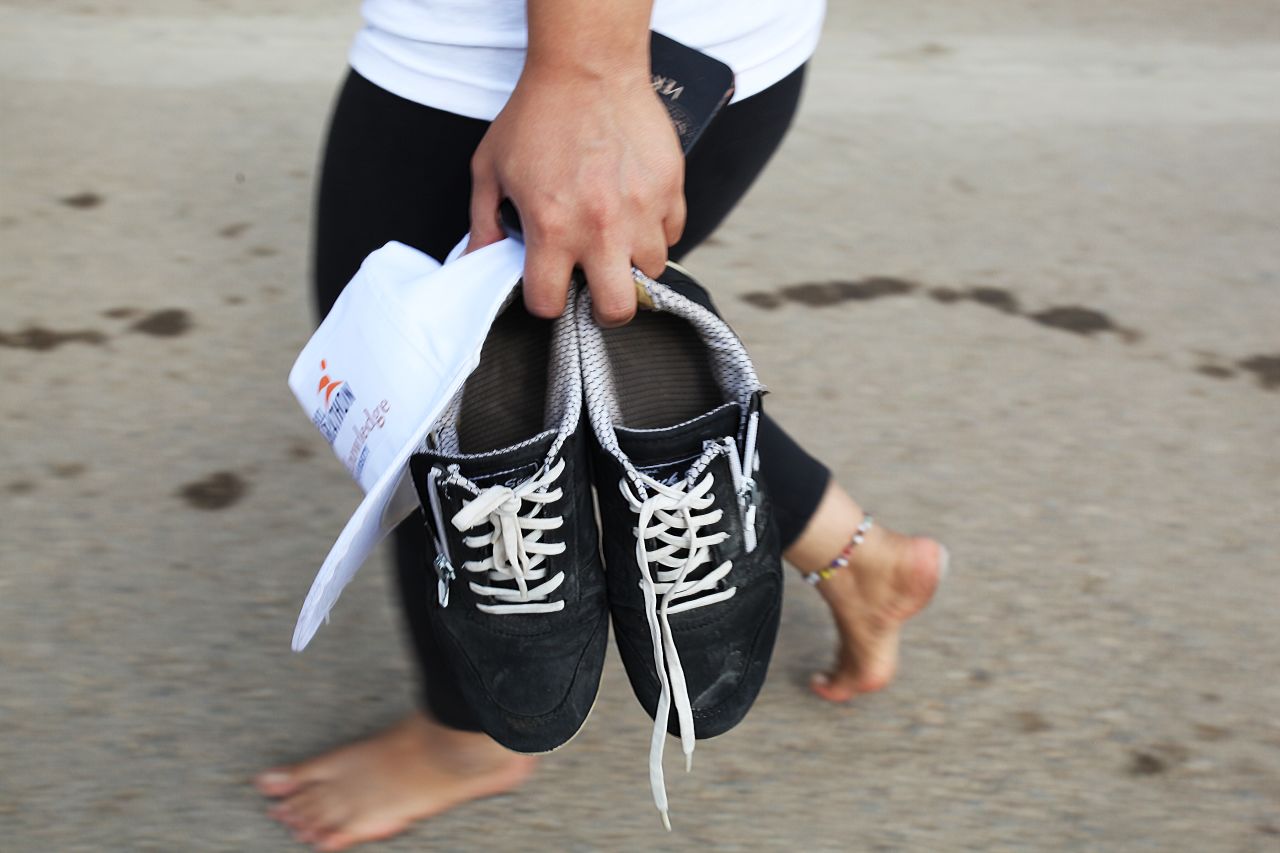 A runner takes off shoes and walks barefoot after the long run.