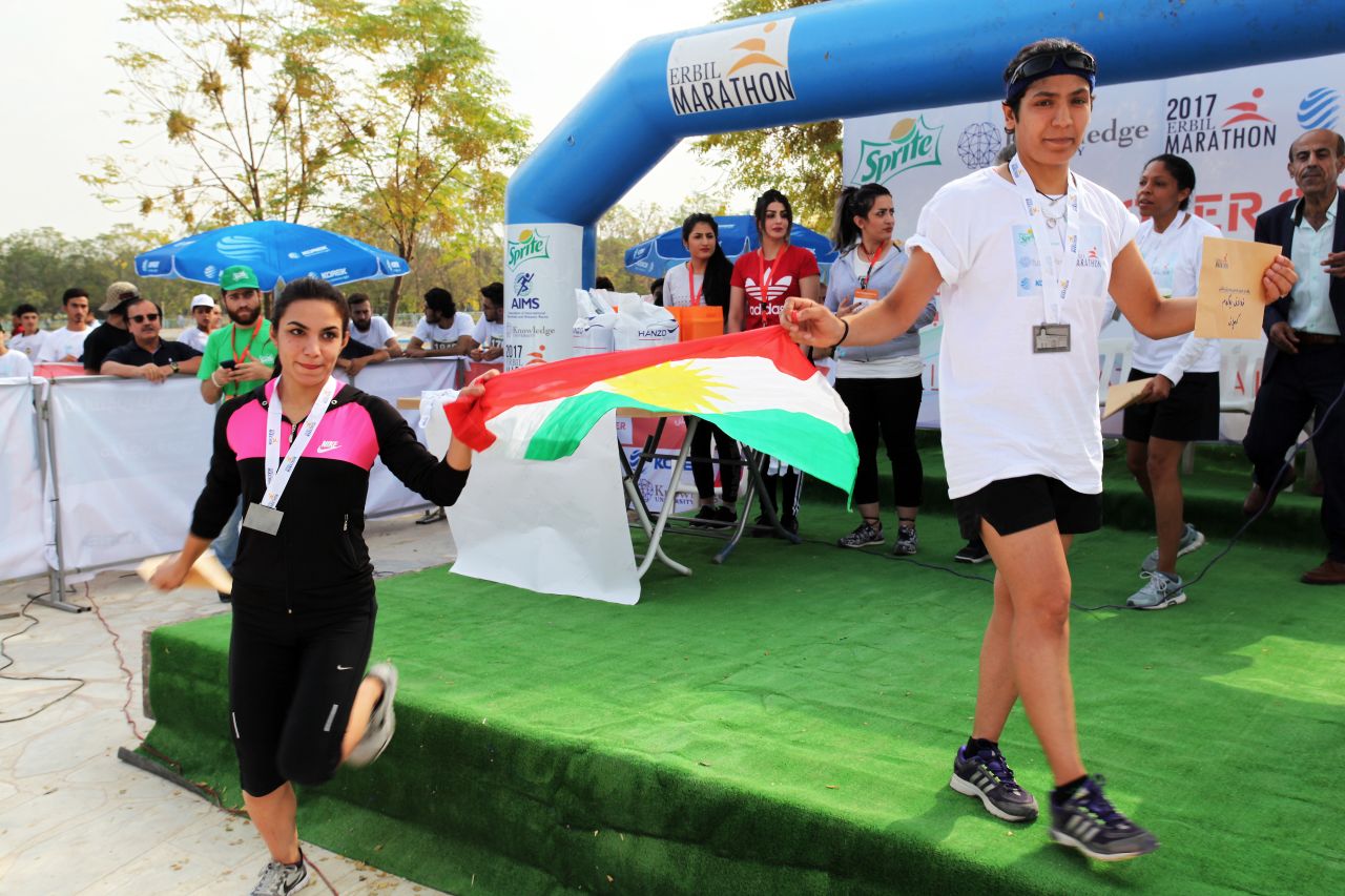 The first and third place winners of the women's race wave the Kurdish flag.
