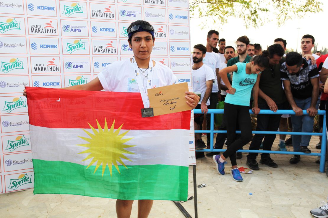 Winner of the women's 10km race, Amal Khidir, takes photos with a Kurdish flag at the awards ceremony. 