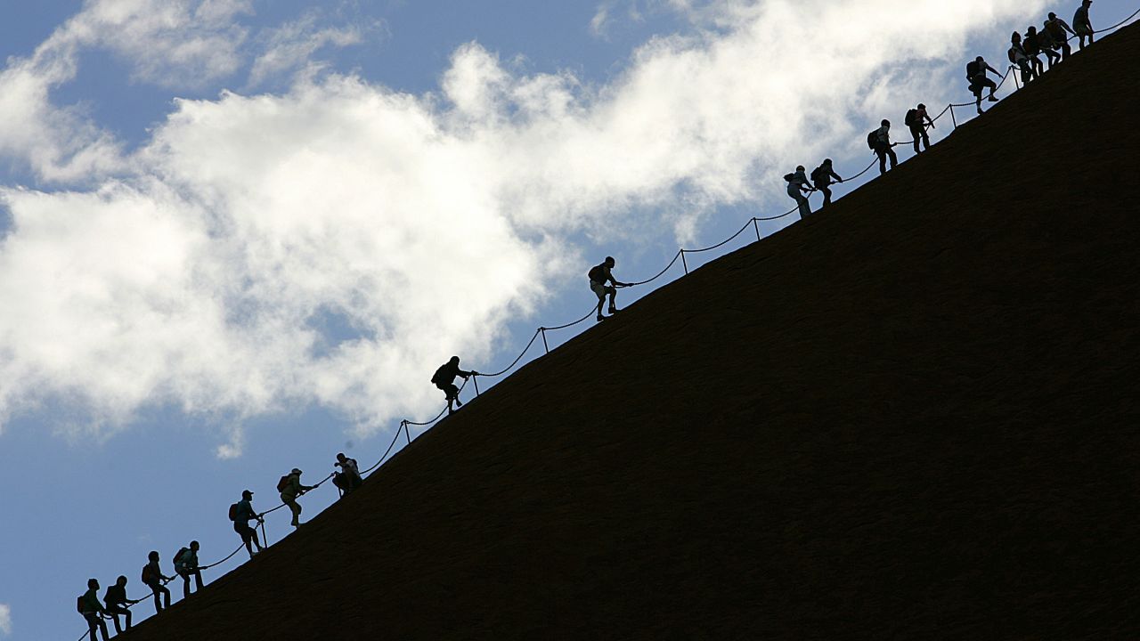 Tourists climb the monolith of Uluru to reach the 340m summit.