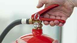white hand presses the trigger fire extinguisher; Shutterstock ID 115760446; PO: CNN Photos