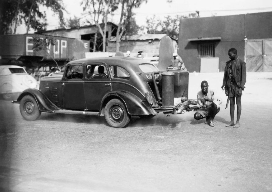 When gasoline imports ceased in Senegal in the 1940s, people had to improvise. Pictured here are two Senegalese men stoking a charcoal-burning automobile called the "Gas-o-gene" in 1942. <br />