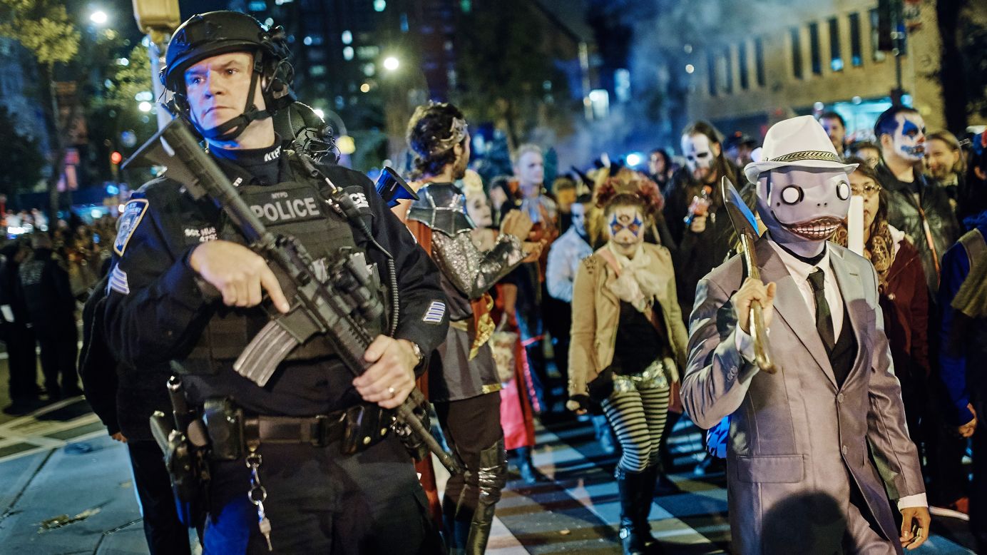 Armed police stand guard in New York City as revelers march during the Greenwich Village Halloween Parade on Tuesday, October 31.