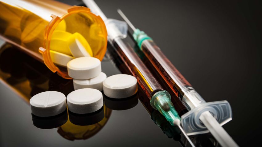 Opioid epidemic, drug abuse concept with closeup on two heroin syringes or other narcotics surrounded by scattered prescription opioids. Oxycodone is the generic name for a range of opioid painkillers; Shutterstock ID 706837198; Job: -