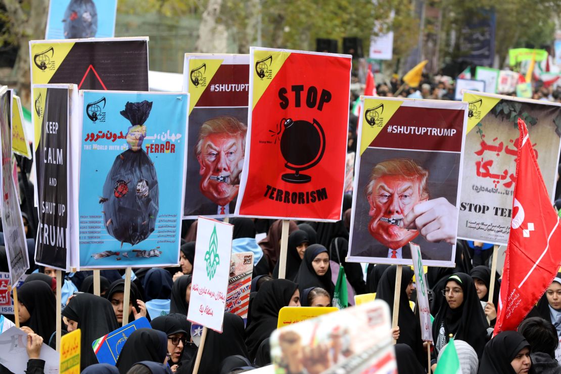 Iranian women carry placards during a protest Saturday outside the former US Embassy in Tehran.