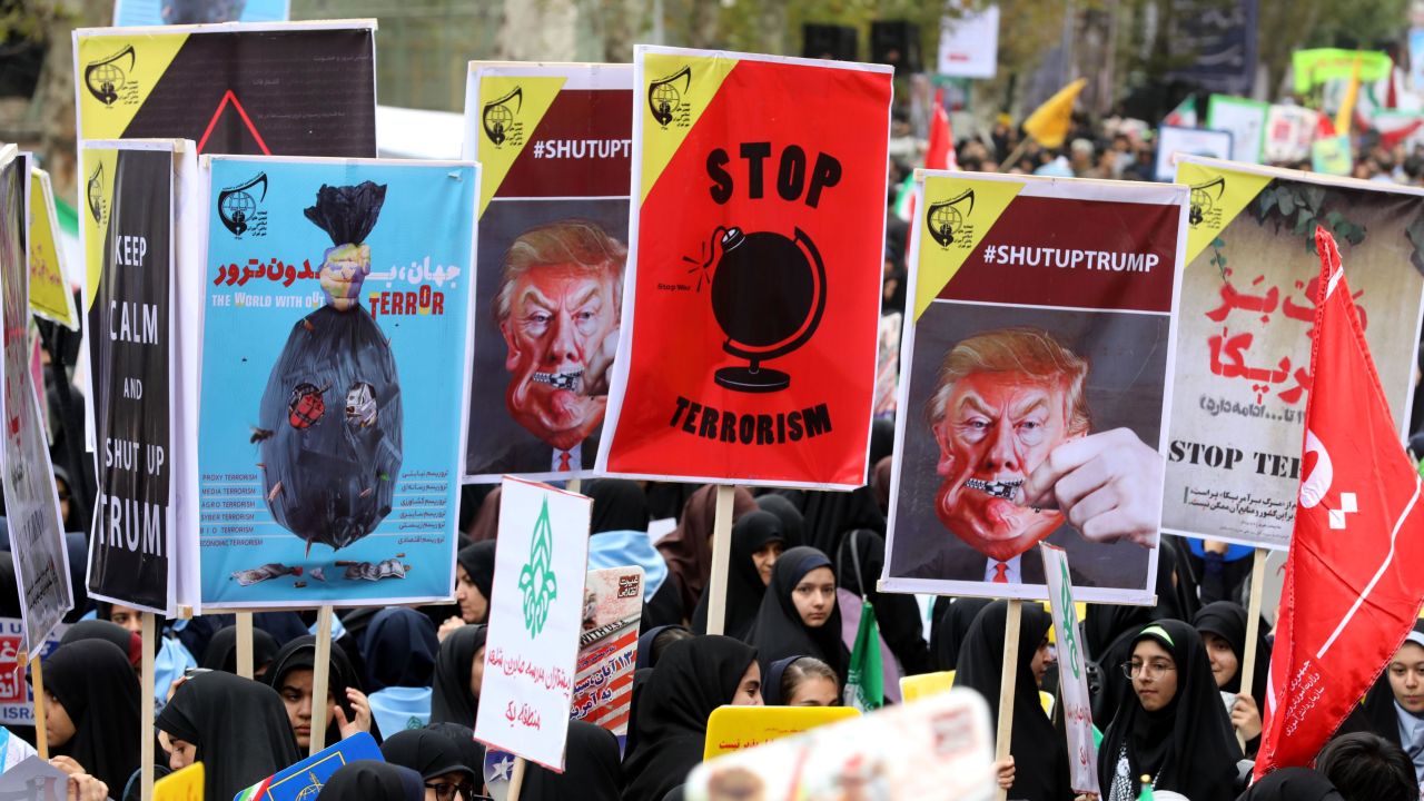 Iranian women carry placards during a protest Saturday outside the former US Embassy in Tehran.