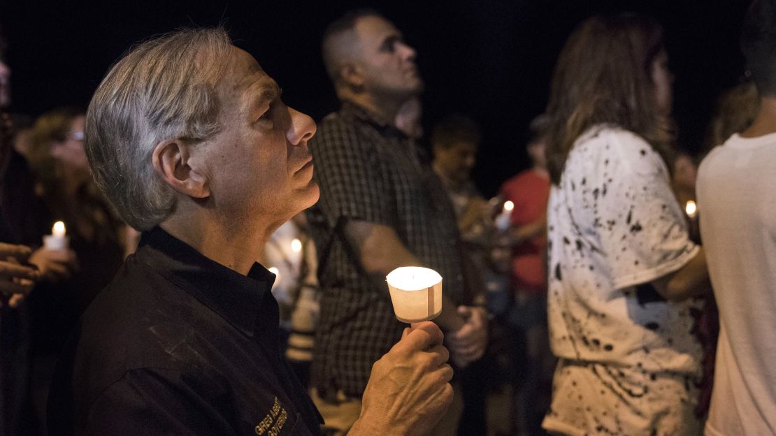 Texas Gov. Greg Abbott participates in a candlelight vigil Sunday for the victims at First Baptist Church.