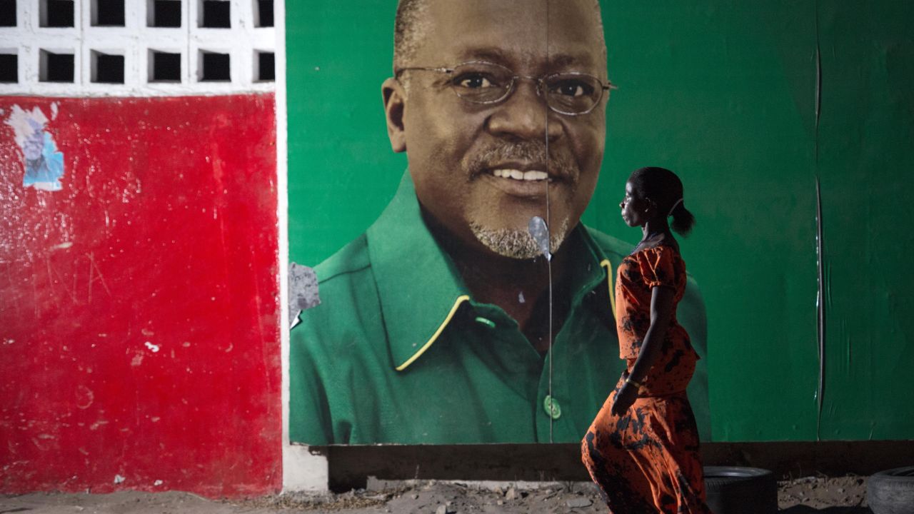A woman walks past an election billboard of candidate John Magufuli. 