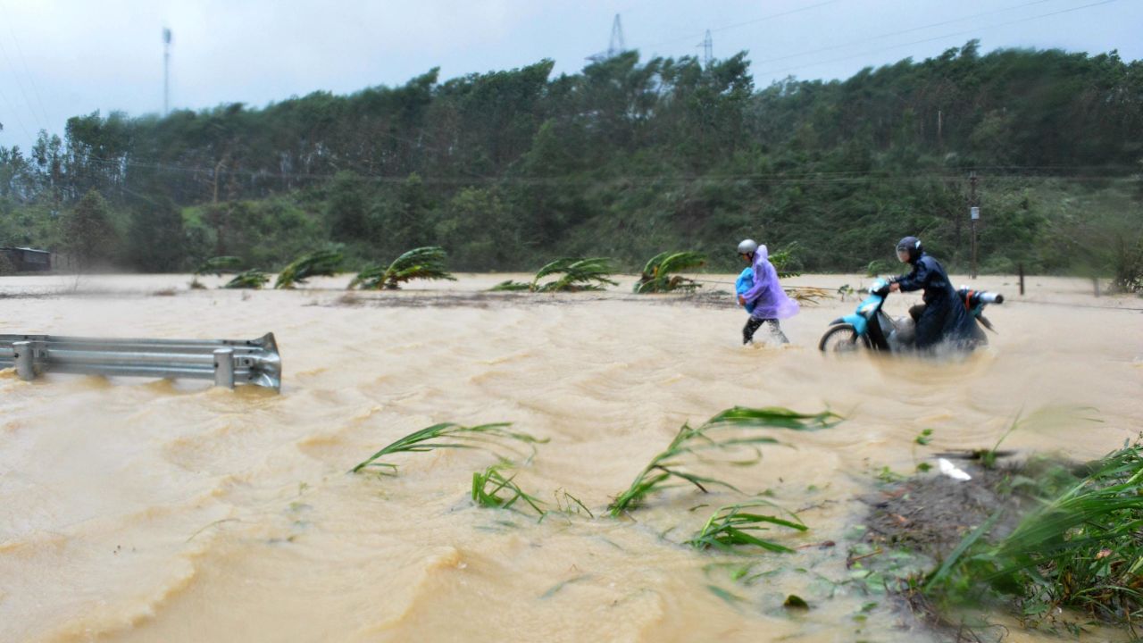 People walk through floodwaters on a highway in the central province of Dak Lak brought by Typhoon Damrey on Saturday.