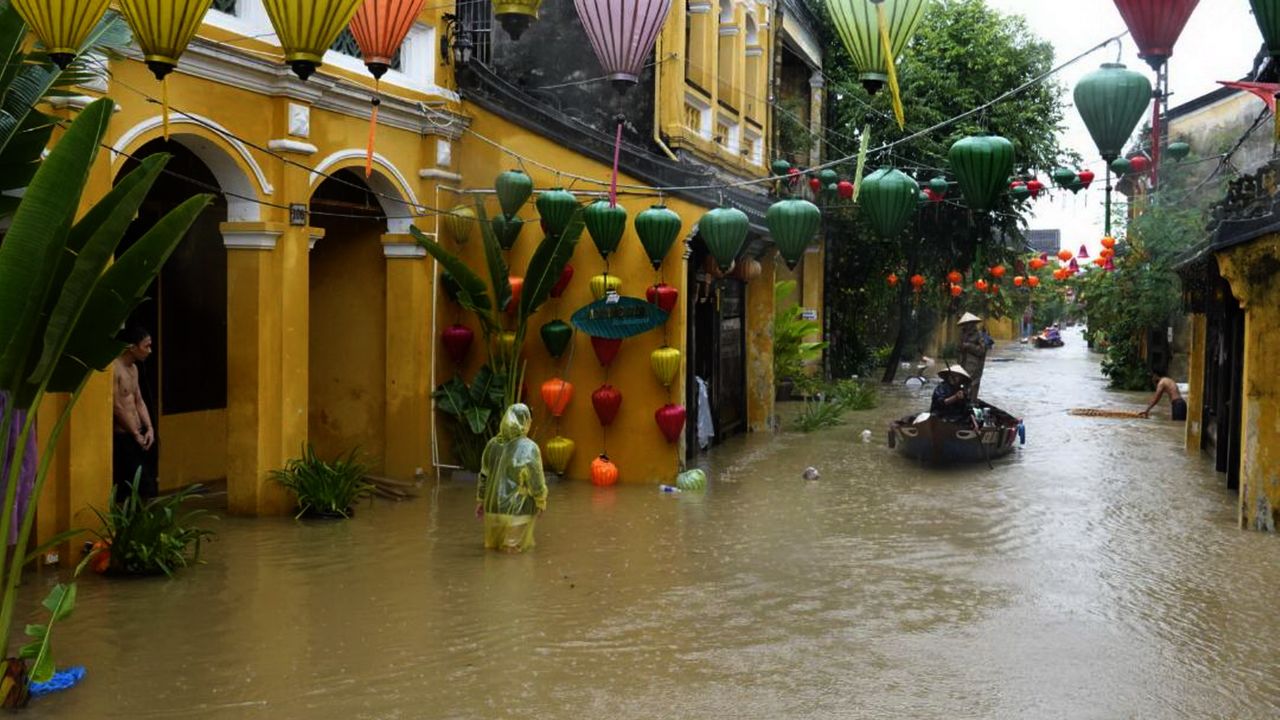 Local residents navigate on a boat as others wade in the flooded town of Hoi An on Sunday.