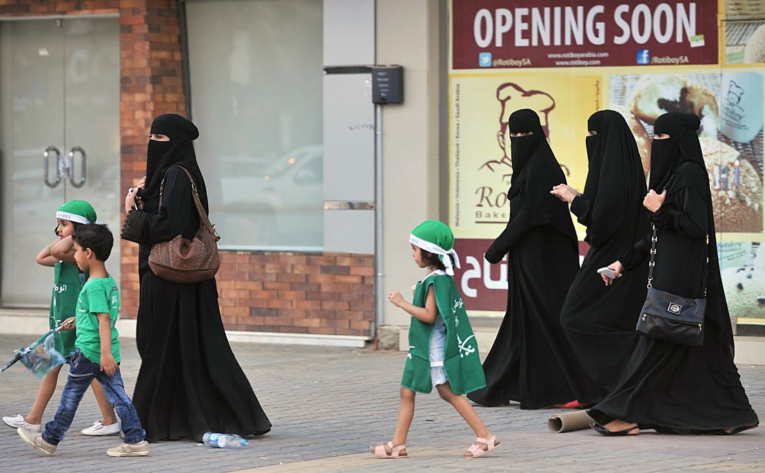 Saudi women and their children walk along a street as they make their way to a celebration rally marking the 83rd Saudi Arabian National Day.