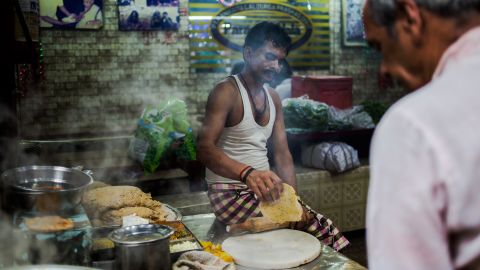 An Indian cook makes parathas, fried stuffed bread, at a shop in Paranthe Wali Gali.