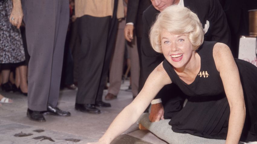 19th January 1961:  American singer and actress Doris Day smiling as she signs her name in cement by her handprints, in front of Mann's (formerly Grauman's) Chinese Theater, on Hollywood Boulevard, Hollywood, California.  (Photo by Hulton Archive/Getty Images)
