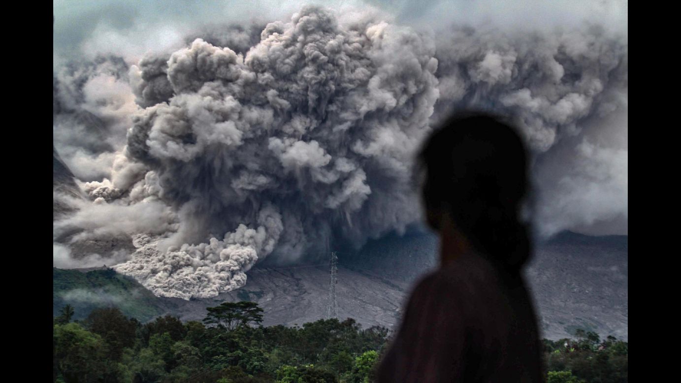 A woman watches Mount Sinabung erupt in Karo, Indonesia, on Friday, November 3. The volcano has been highly active since 2010.