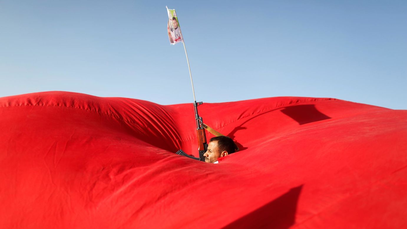 A man is seen in the gap of a flag as he attends a pro-Palestinian rally in Sanaa, Yemen, on Monday, November 6.