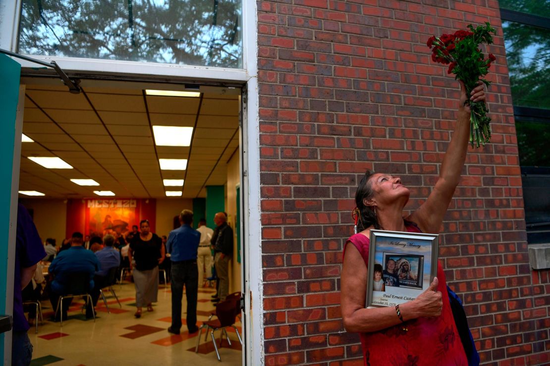 Lynn Eagle Feather holds a bouquet to the sky while clutching a picture in memory of her son Paul Castaway.