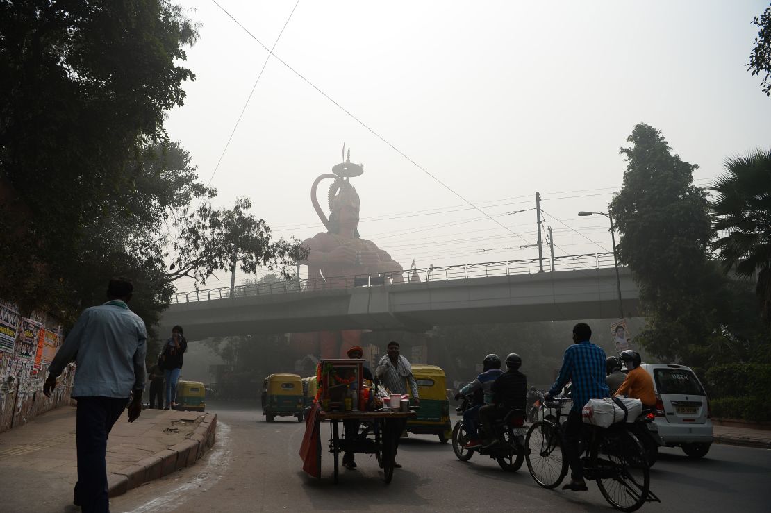 Indian commuters drive past the city's famous Hanuman Temple amid heavy smog.
