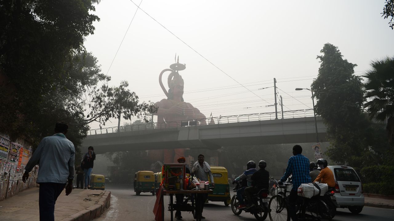 Indian commuters drive past the city's famous Hanuman Temple amid heavy smog.

