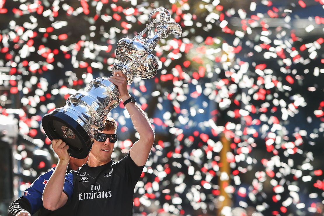 Peter Burling holds aloft the oldest trophy in sport