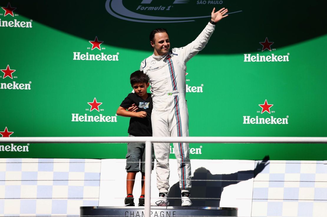 Felipe Massa, alongside son Felipinho, waves to the home fans after his final F1 race at Interlagos.
