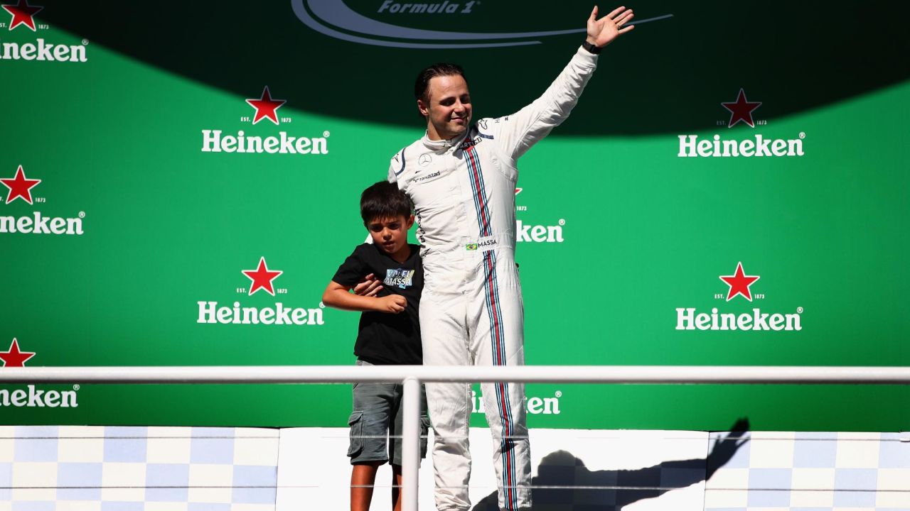 Felipe Massa, alongside son Felipinho, waves to the home fans after his final F1 race at Interlagos.