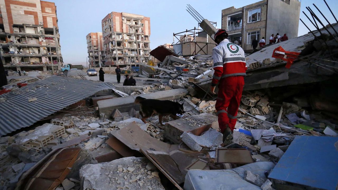 In this photo provided by the Iranian Students News Agency, ISNA, a rescue worker searches debris for survivors with his sniffing dog after an earthquake at the city of Sarpol-e-Zahab in western Iran, Monday, Nov. 13, 2017. A powerful earthquake shook the Iran-Iraq border late Sunday, killing more than two hundreds people, Iranian state media said. (Pouria Pakizeh/ISNA via AP)