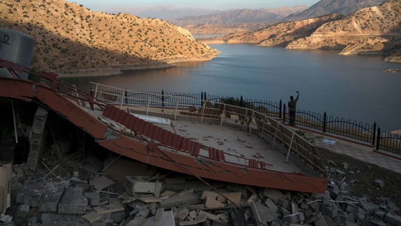A man takes a picture of a destroyed structure near Iraq's Darbandikhan Lake on November 13.