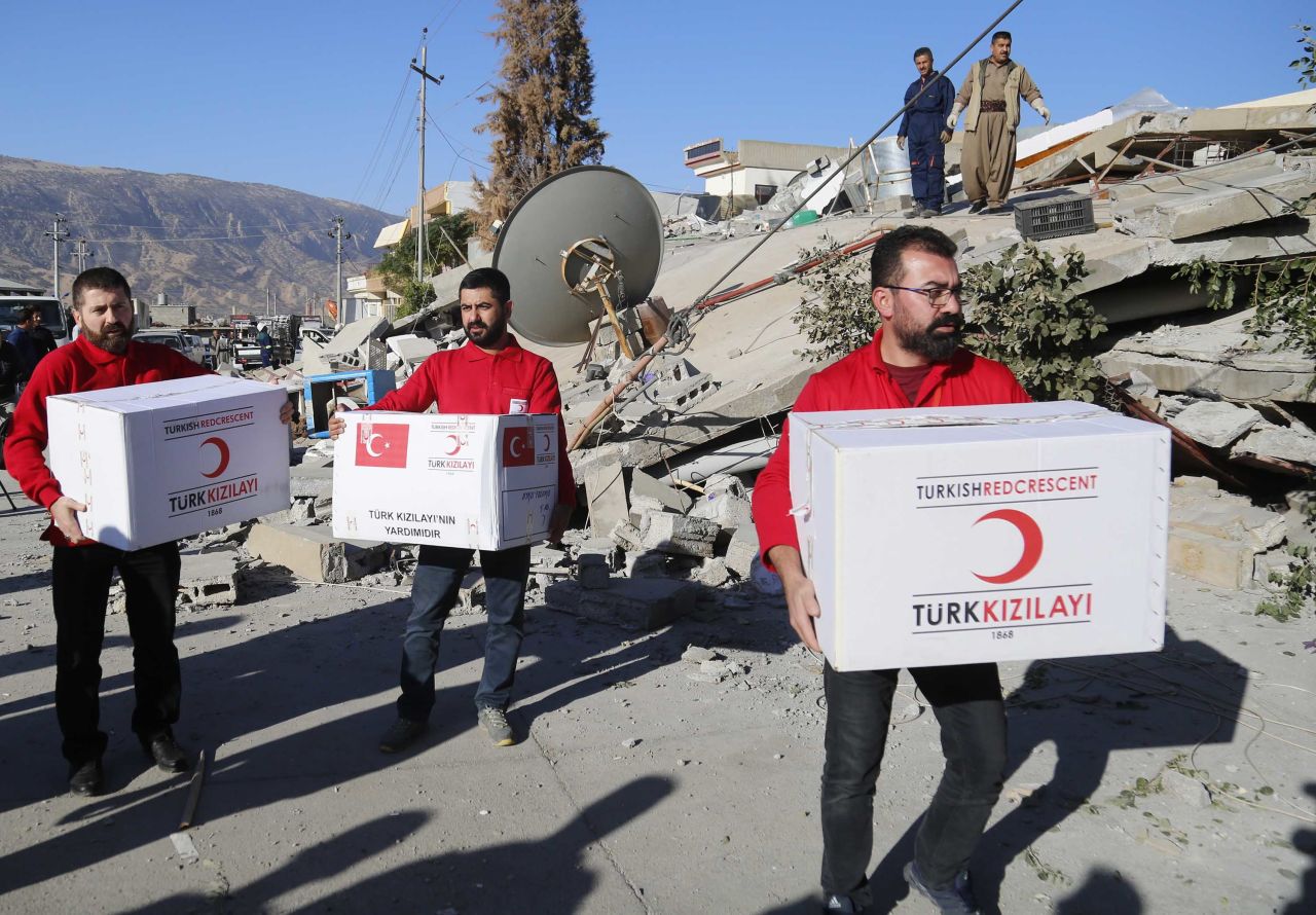 Members of the Turkish Red Crescent distribute aid to quake survivors in Iraq's Darbandikhan district on November 13.<br />