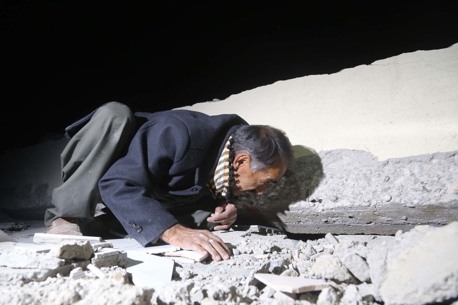 A man searches for people trapped in the rubble in Iraq's Darbandikhan district on Sunday, November 12.