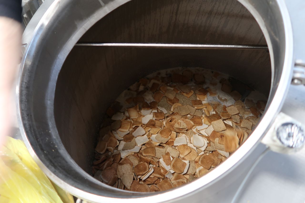The bread is combined with malted barley, oat husks, and water. The mixture is heated in a process known as mashing.<br />