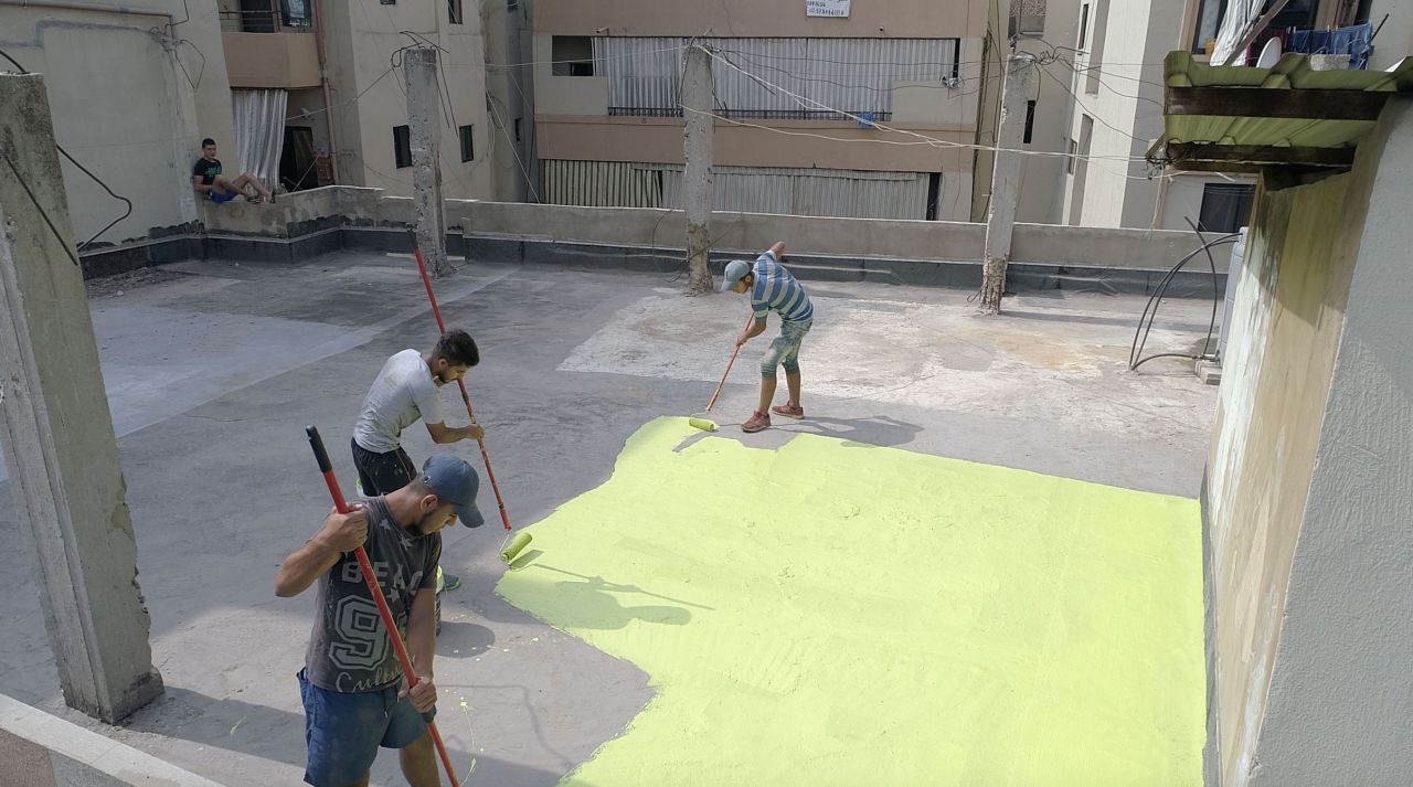 Men paint a roof in the city of Tripoli, Lebanon, as part of the Operation Salam graffiti project.