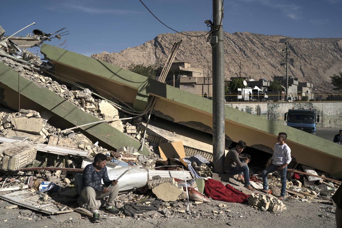 People sit on the rubble of a destroyed house after an earthquake in the city of Darbandikhan, northern Iraq.
