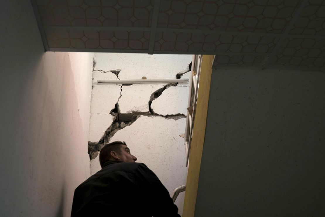 A man checks the interior of a damaged house after an earthquake in the city of Darbandikhan.