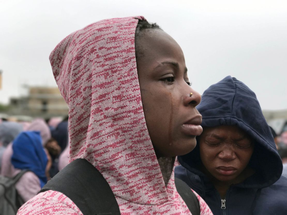 A woman cries as she is told she must leave her husband behind because he has yet to receive proper paperwork.