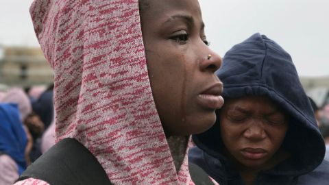 A woman cries as she is told she must leave her husband behind because he has yet to receive proper paperwork.