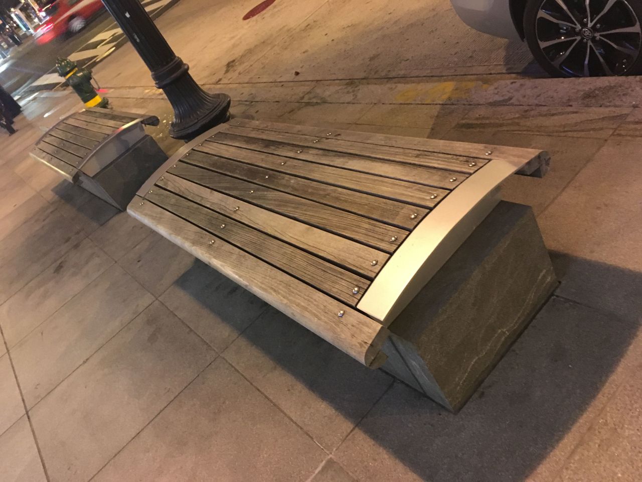 Sometimes hostile architecture is subtle. Instead of unwelcoming armrests, this wooden bench is designed with a curved base, to prevent users from lying down on it.