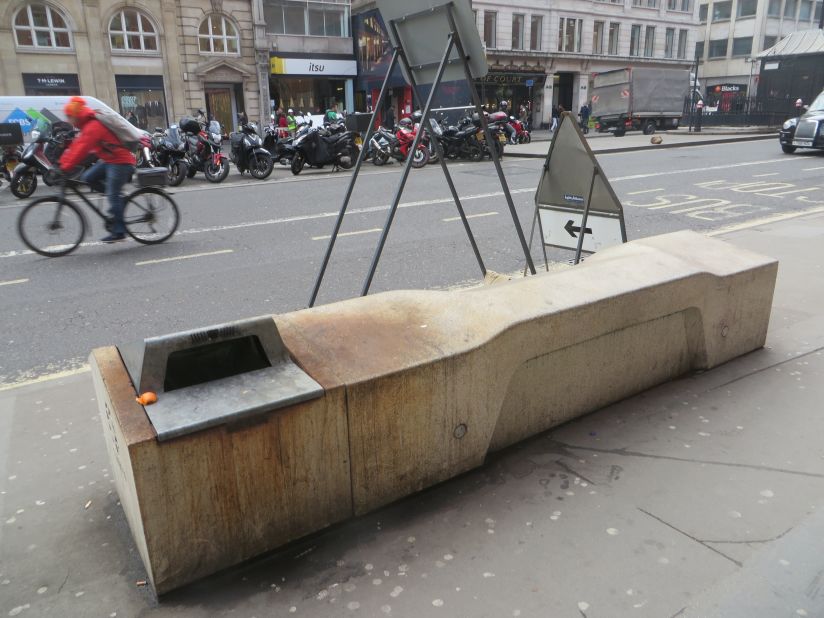 A rusty garbage bin at the end of this bench makes it an unpleasant environment for those hoping to rest on it.